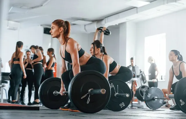 A group of people lifting barbells together in a gym