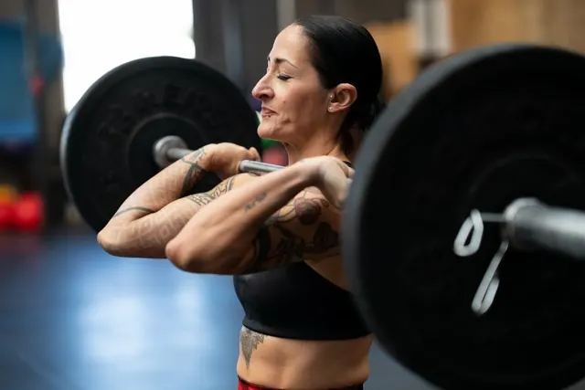 A woman lifting a barbell in a gym