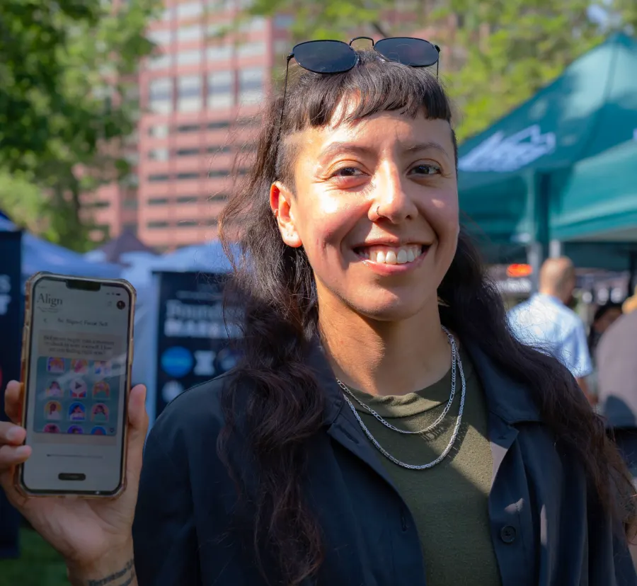 Zulma Y. Terrones holding a phone showing the Align app at an outdoor market